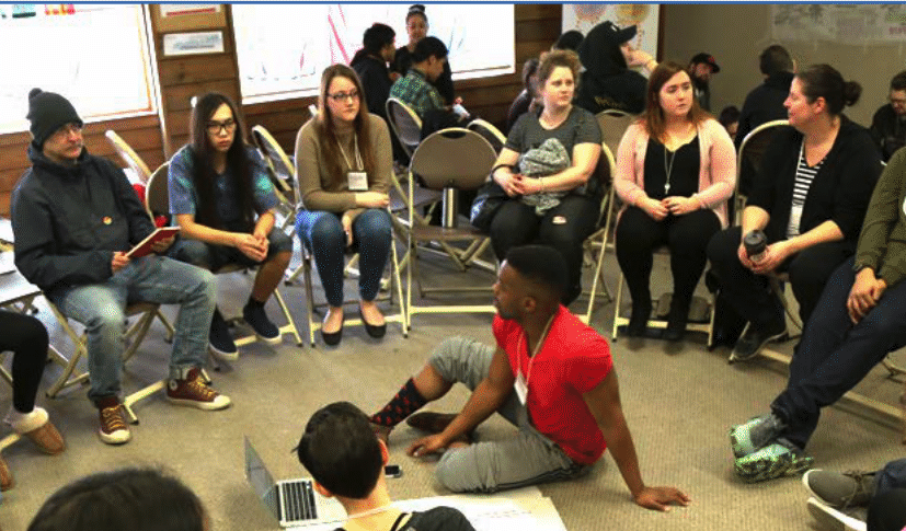 a group of people sitting in a circle, possibly in a discussion or workshop setting